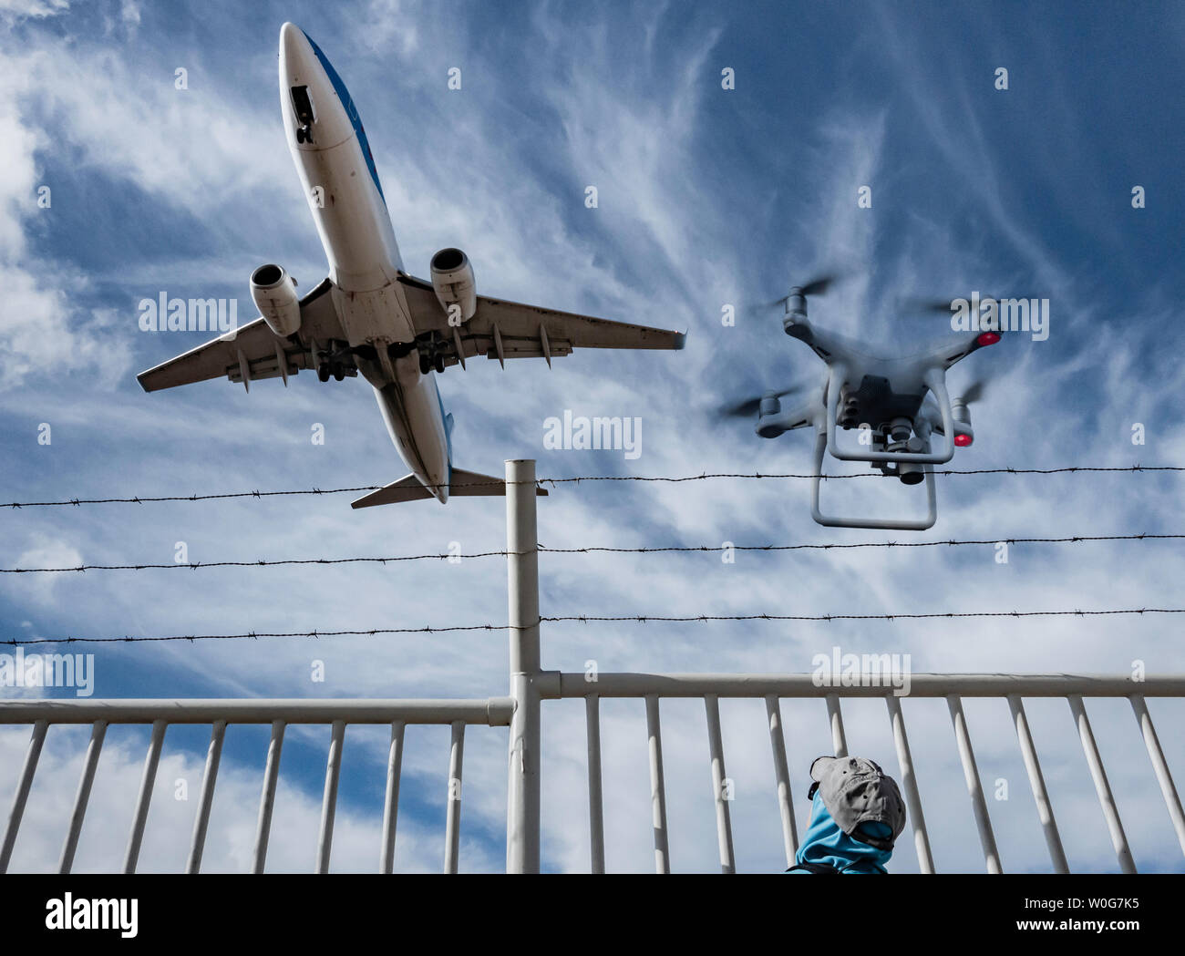 Woman watching aircraft/airplane from behind barbed wire perimeter, border fence. Concept image: Russia Ukraine conflict, no fly zone, refugee crisis. Stock Photo