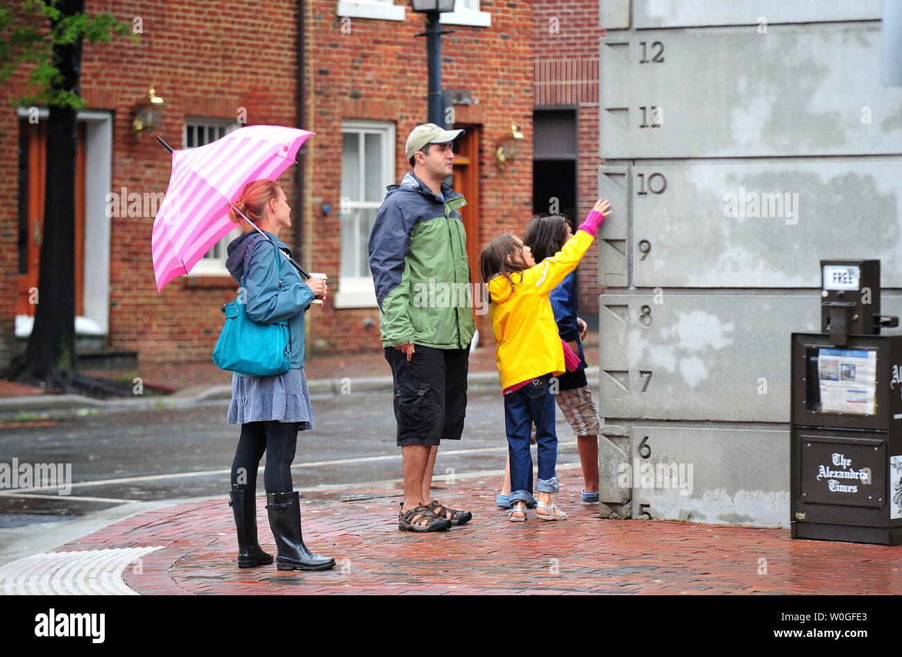A family looks at a flood water gage in Old Town Alexandria, Virginia on August 28, 2011.  Hurricane Irene passed through the Washington Metro Area last night dropping over three inches of rain but did little damage. The storm has now been downgraded to a tropical storm as it heads towards New York.  UPI/Kevin Dietsch Stock Photo