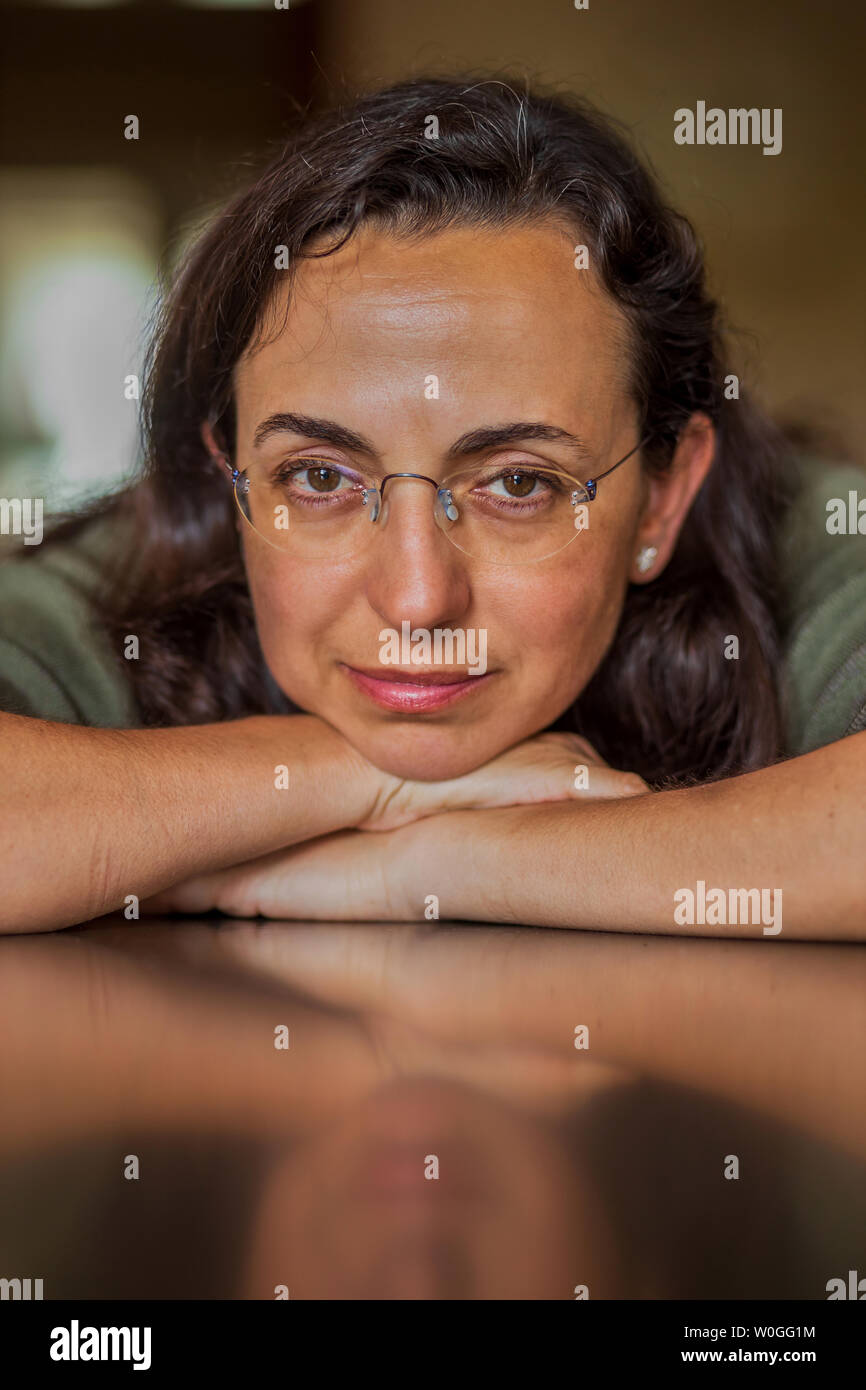 Pretty Spanish woman with glasses at home in front of the camera Stock