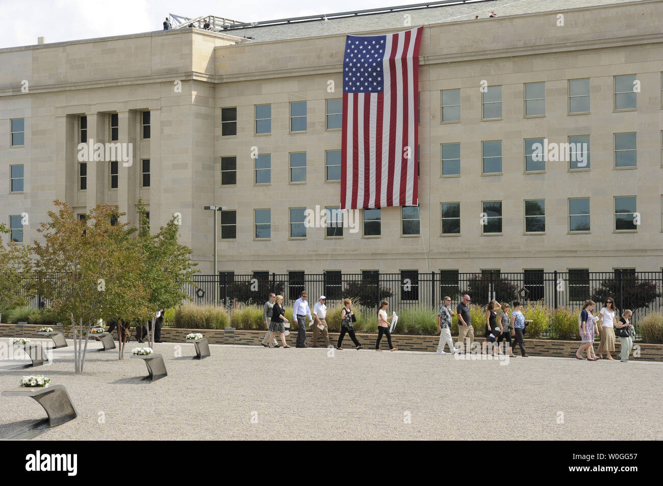 Family members of victims lost during the Pentagon attack walk through the Pentagon Memorial gardens, where wreaths were placed for each victim, and under a large American flag unfurled from the roof of the Pentagon duriing the the 10th anniversary ceremony, September 11, 2011, in Arlington, Virginia.  On September 1, 2001, high-jacked American Airlines flight 77 crashed into the Pentagon, killing all 64 passengers on board and 125 in the Pentagon.   UPI/Mike Theiler Stock Photo