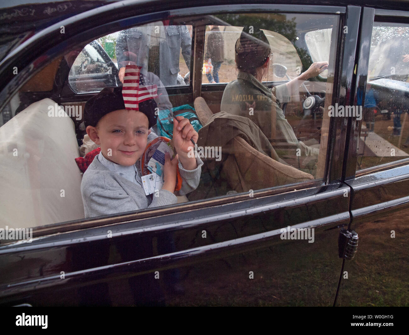 In Normandy a boy waves an American flag at at an event commemorating the D-Day landings Stock Photo