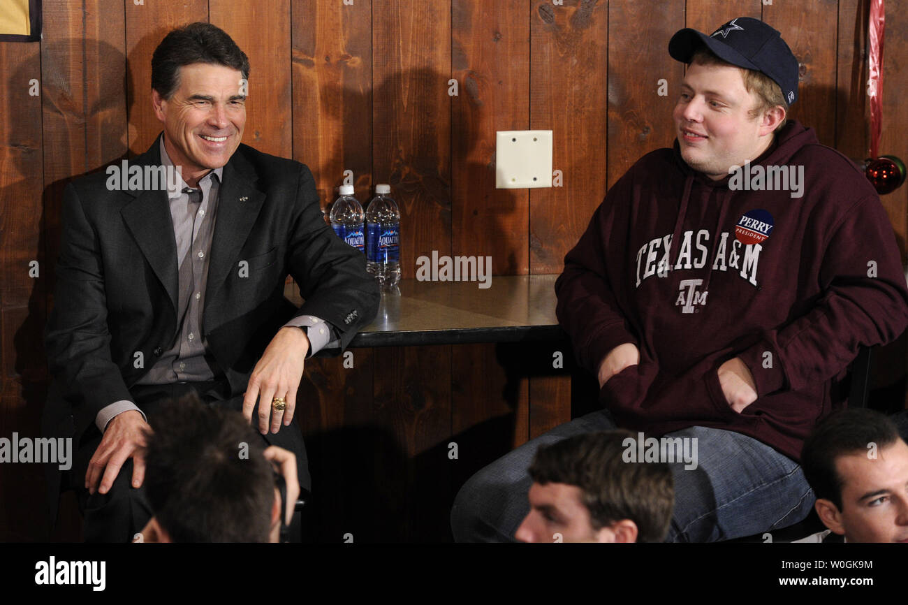 Republican 2012 presidential candidate and Texas Gov. Rick Perry (L) takes a seat next to Robert Loewen, 21, of Minneapolis, Minnesota, who is wearing Perry's alma mater Texas A&M University garb, as he arrives for a campaign stop at The Fainting Goat Bar and Grill in Waverly, Iowa, December 30, 2011, in advance of Iowa's first-in-the-nation caucuses, January 3,2012.    UPI/Mike Theiler Stock Photo