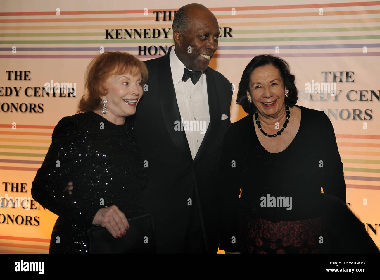 Vernon Jordan (C), his wife Anne (R) and socialite Buffy Cafritz pose for photographers on the red carpet as they arrive at the Kennedy Center for the Performing Arts for a gala evening for the 2011 Kennedy Center Honorees, December 4, 2011, in Washington. The Kennedy Center annually salutes a select group for their contributions to the performance arts in America.     UPI/Mike Theiler Stock Photo