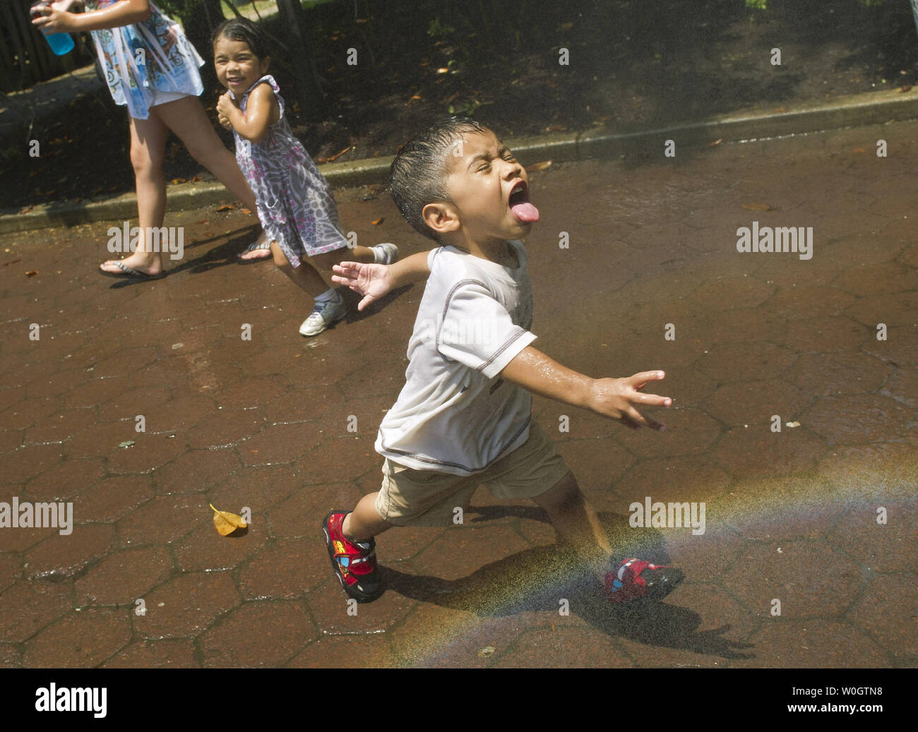 Neaster Rodas, 2, and his sister Sarah cool off from the oppressive heat in a mister at the National Zoo on June 29, 2012 in Washington, D.C. Temperatures are expected to hover around 100 degrees through the weekend.  UPI/Kevin Dietsch Stock Photo