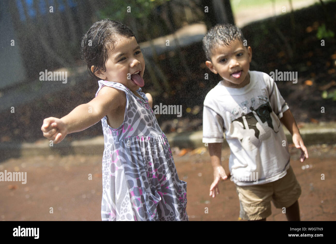 Sarah Rodas, 4, and her brother Nester, 2, sister cool off from the oppressive heat in a mister at the National Zoo on June 29, 2012 in Washington, D.C. Temperatures are expected to hover around 100 degrees through the weekend.  UPI/Kevin Dietsch Stock Photo