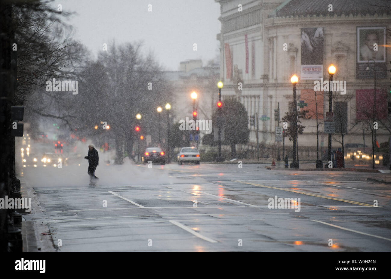 A person crosses the street as snow and rain falls on March 6, 2013 in Washington, D.C. Meteorologist are predicting anywhere from five to ten inches of snow to fall inside the Capital Beltway, and significantly more further north and west.  UPI/Kevin Dietsch Stock Photo