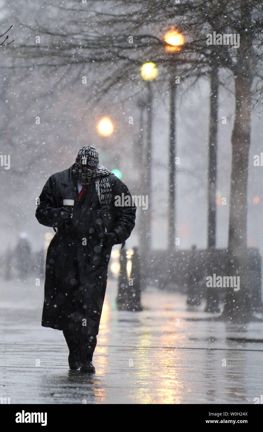 A man walks on 17th Street as snow and rain begin to fall on March 6, 2013 in Washington, D.C. Meteorologist are predicting anywhere from five to ten inches of snow to fall inside the Capital Beltway, and significantly more further north and west.  UPI/Kevin Dietsch Stock Photo