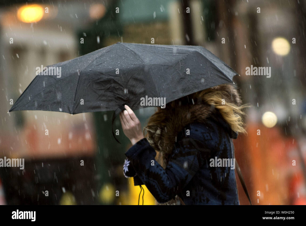 A woman shields herself from rain and snow on March 6, 2013 in Washington, D.C. Despite a slow start meteorologist are predicting anywhere from five to ten inches of snow to fall inside the Capital Beltway, and significantly more further north and west.  UPI/Kevin Dietsch Stock Photo