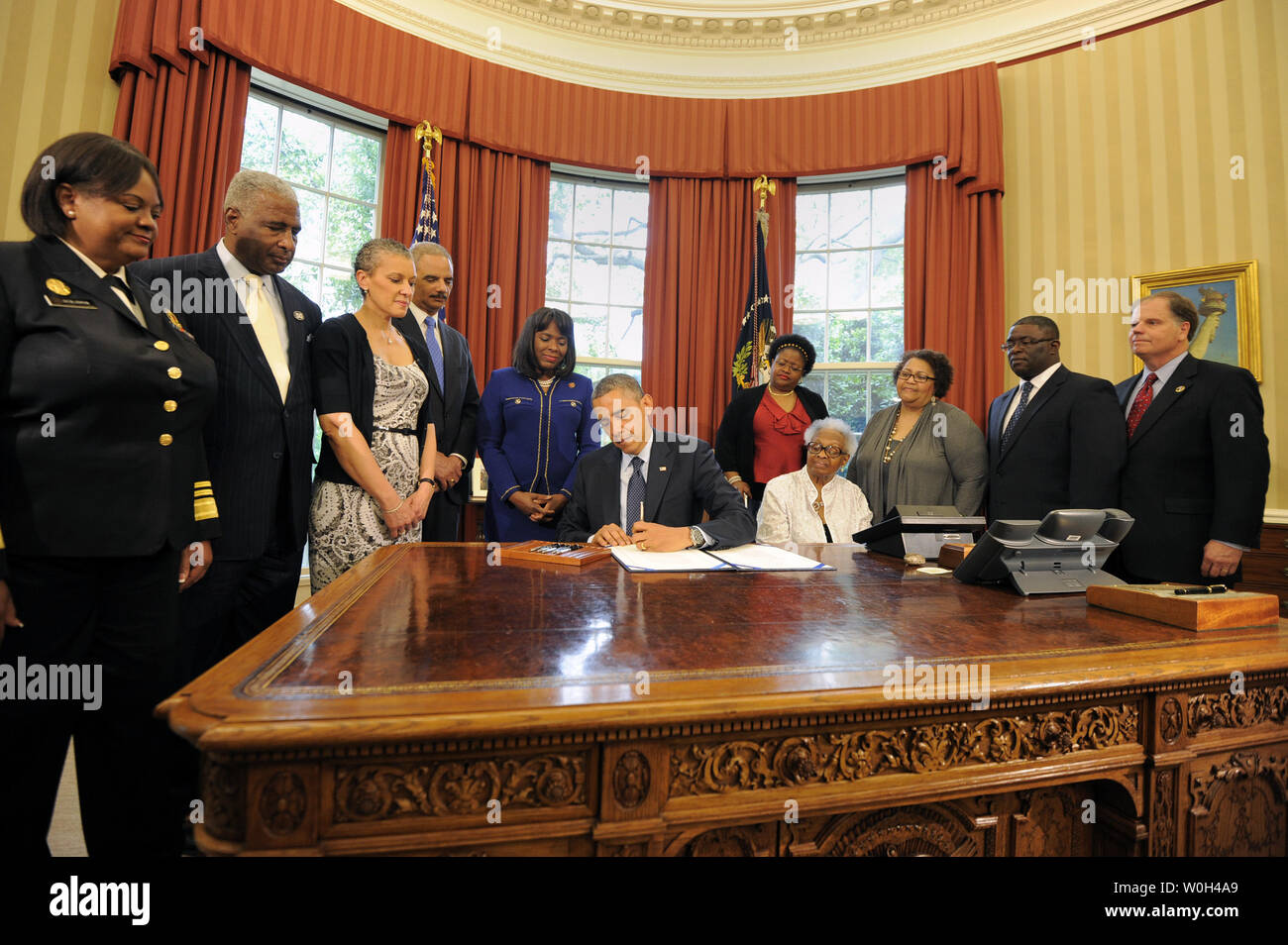 US President Barack Obama signs a bill in the Oval Office, May 24, 2013 in Washington, DC designating the Congressional Gold Medal commemorating the lives of the four young girls killed in the 16th Street Baptist Church Bombings of 1963 in Birmingham, Alabama. Witnessing (L-R) Surgeon General Regina Benjamin, Birmingham Mayor William Bell, Dr Sharon Malone Holder, Attorney General Eric Holder, Rep Terri Sewell (D-AL), Thelma Pippen McNair (mother of Denise McNair), Lisa McNair (sister of Denise McNair), Dianne Braddock (sister of Carolel Robertson), Rev Arthur Price, Jr (pastor 16th Street Bap Stock Photo