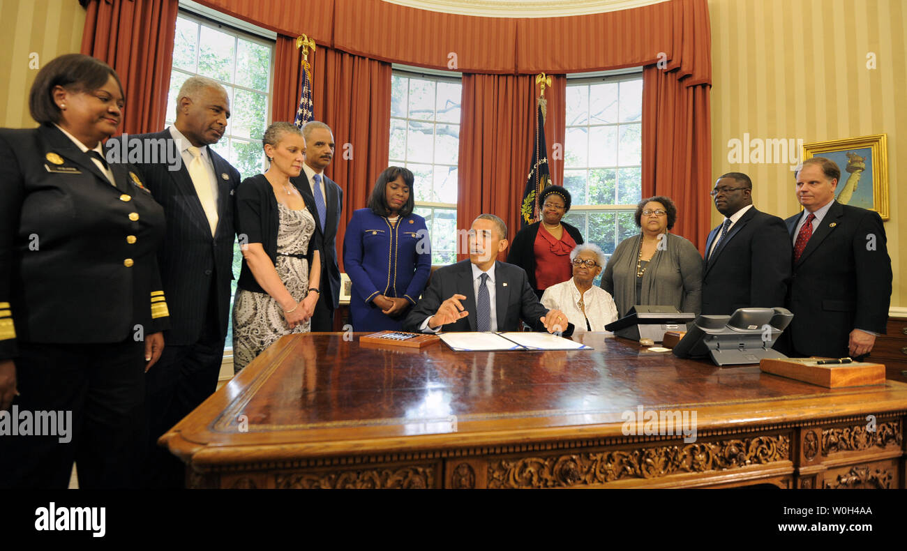 US President Barack Obama makes remarks before he signs a bill in the Oval Office, May 24, 2013 in Washington, DC designating the Congressional Gold Medal commemorating the lives of the four young girls killed in the 16th Street Baptist Church Bombings of 1963 in Birmingham, Alabama. Witnessing (L-R) Surgeon General Regina Benjamin, Birmingham Mayor William Bell, Dr Sharon Malone Holder, Attorney General Eric Holder, Rep Terri Sewell (D-AL), Thelma Pippen McNair (mother of Denise McNair), Lisa McNair (sister of Denise McNair), Dianne Braddock (sister of Carole Robertson), Rev Arthur Price, Jr Stock Photo