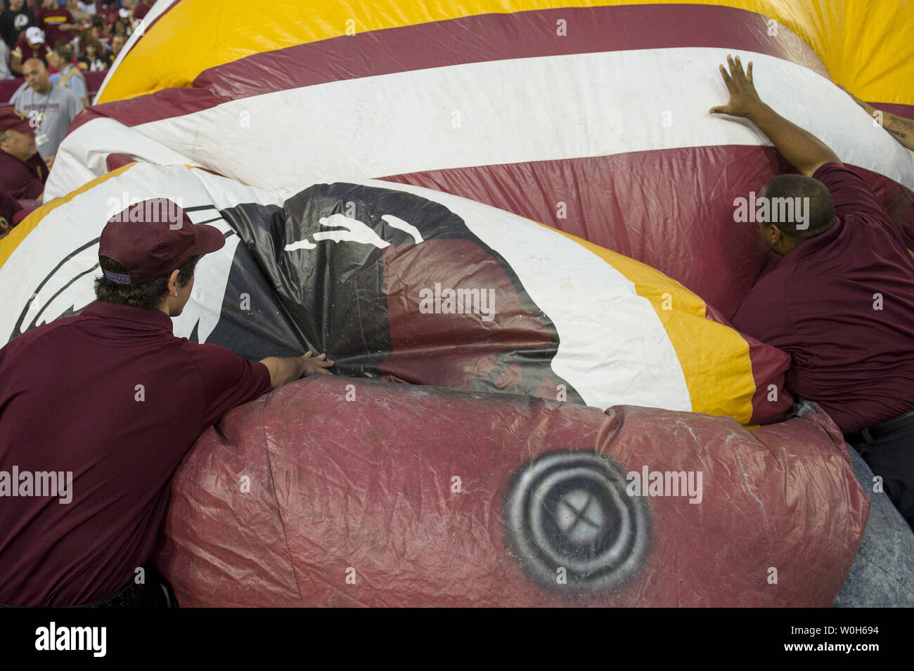 Members of the Washington Redskins staff deflate a giant Redskins helmet during pre-game activities prior to the Redskins game against the Pittsburgh Steelers at FedEx Field in Landover, Maryland on August 19, 2013.  UPI/Kevin Dietsch Stock Photo