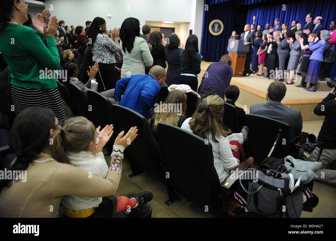 Hope Katz-Zogby, age 3, applauds with her mother Elizabeth (L) as they listen to U.S. President Barack Obama discuss the successes of the Affordable Care Act in the Eisenhower Executive Office Building in Washington, DC on December 3, 2013.   Hope, from Baltimore, Maryland, has Down Syndrome but is guaranteed health insurance under the ACA, since insurance companies cannot bar anyone with pre-existing medical conditions. Obama promised that his signature healthcare law was going to remain as long as he was president and that the troubled www.healthcare.gov website was working well for the vast Stock Photo