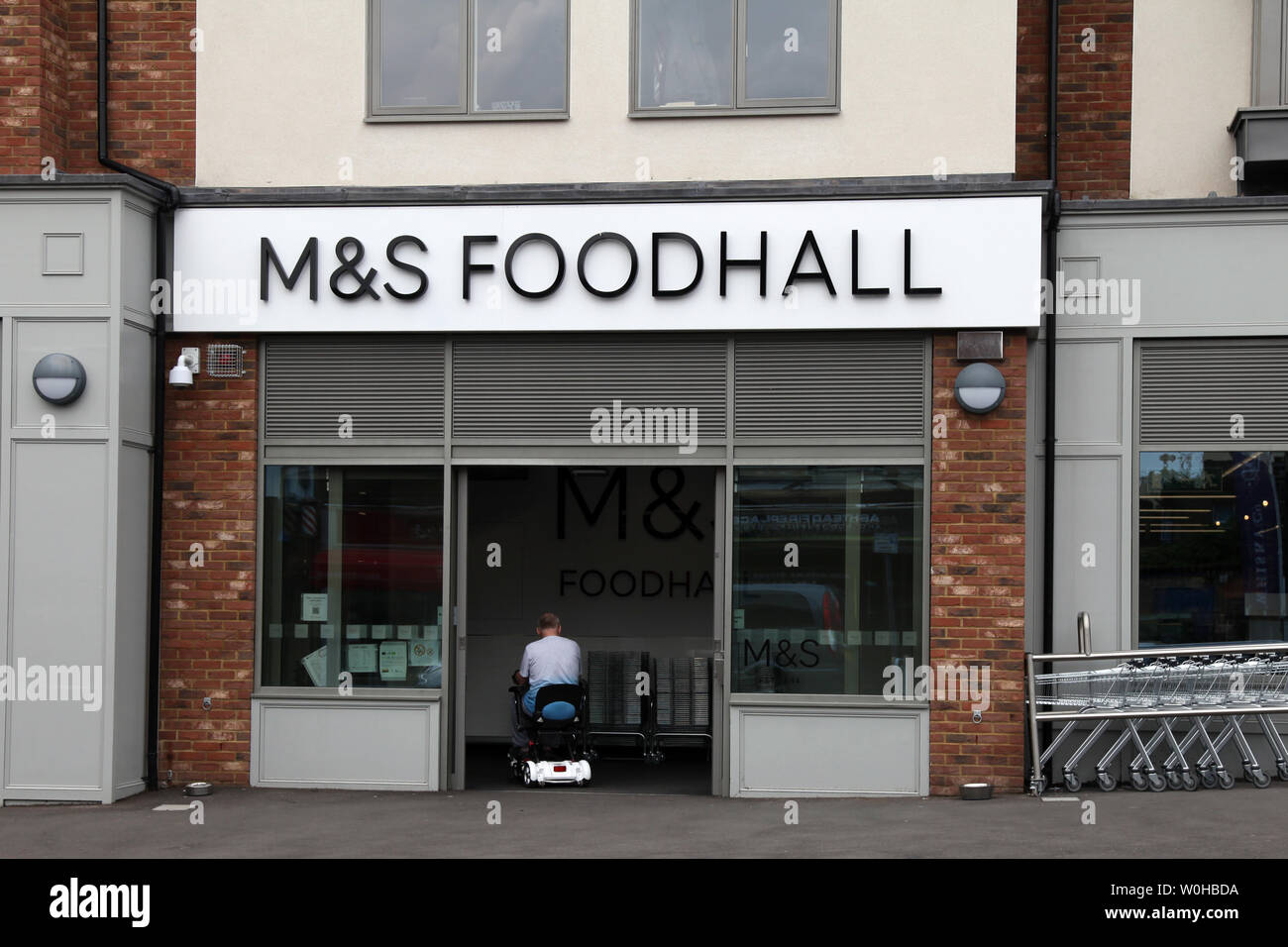 Ashtead, Surrey, UK - Marks and Spencer M&S Foodhall store front exterior on the high street with disabled customer entering on a mobility scooter Stock Photo