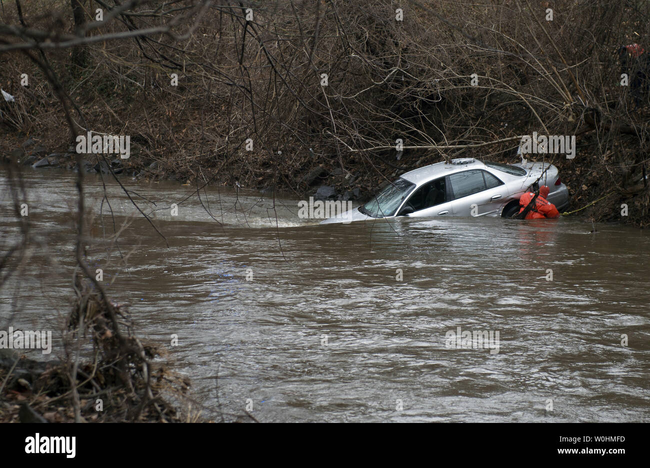 A first responder attempts to attach a chain to pull a car out to Rock