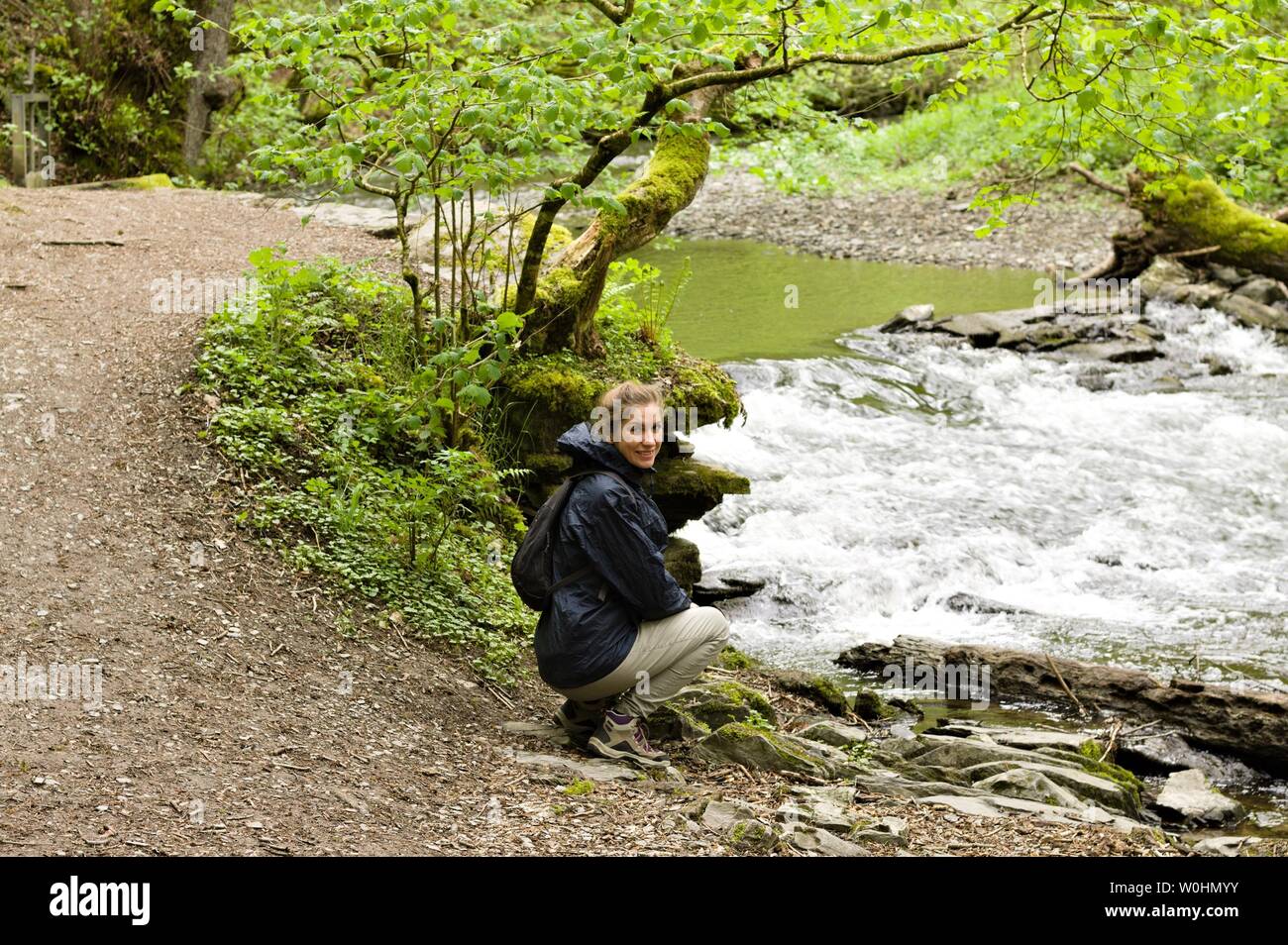 Moselkern, Germany - 26 April 2019: A blonde girl sitting near the Elzbach river Stock Photo