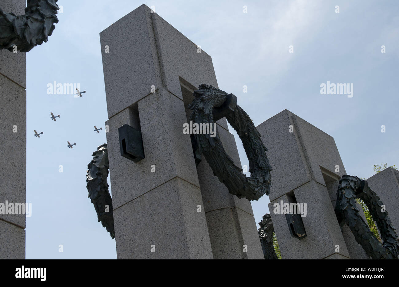 World War II era aircraft flies over the National World War II Memorial ...