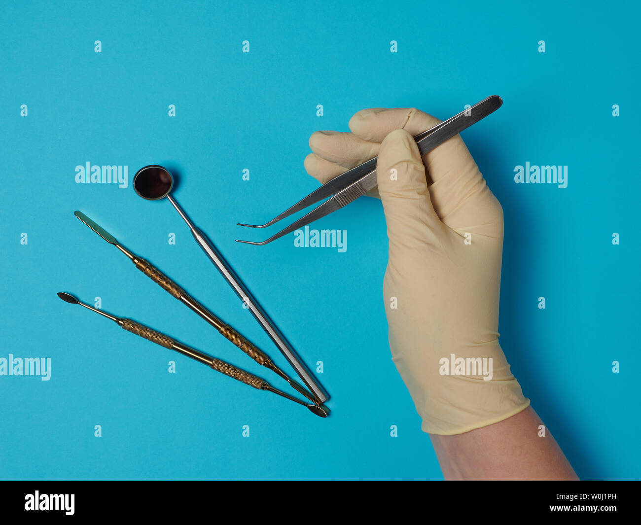 Dental instruments in tray and dentist hand on blue background Stock