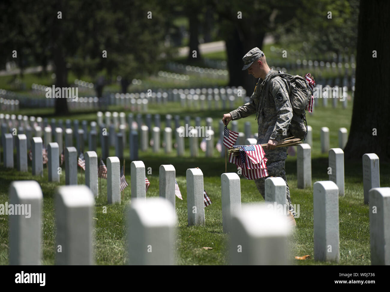 A soldier with the U.S. Army 3rd Infantry Regiment (Old Guard) places a flag at a grave marker as part of the annual Flags-In event for Memorial Day at Arlington National Cemetery in Arlington, Virginia on May 26, 2016. Members of The Old Guard placed an America flag at more than 230,000 grave markers at Arlington in honor of of Nation's fallen military members. The tradition has been conducted since 1948. Photo by Kevin Dietsch/UPI Stock Photo