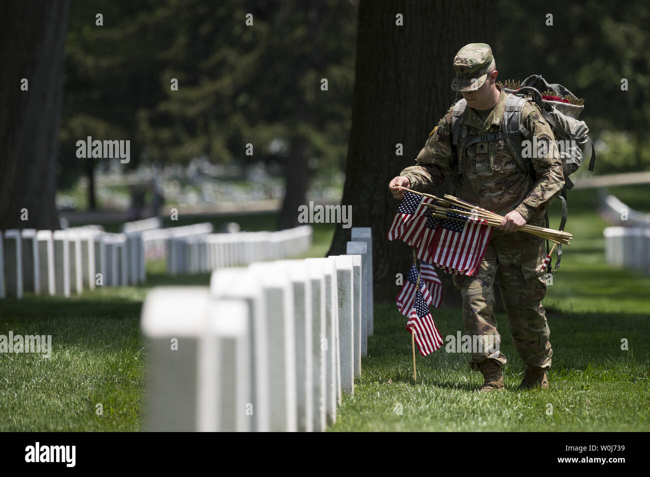 A soldier with the U.S. Army 3rd Infantry Regiment (Old Guard) places a flag at a grave marker as part of the annual Flags-In event for Memorial Day at Arlington National Cemetery in Arlington, Virginia on May 26, 2016. Members of The Old Guard placed an America flag at more than 230,000 grave markers at Arlington in honor of of Nation's fallen military members. The tradition has been conducted since 1948. Photo by Kevin Dietsch/UPI Stock Photo