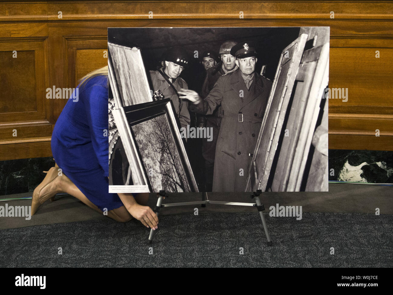 A Senate staffer adjusts World War II era photos of American soldiers recovered Nazi stolen artwork prior to a Senate Judiciary subcommittee hearing on the  HEAR Act, legislation aimed at helping Holocaust survivors and their families recover art stolen by the Nazis, on Capitol Hill in Washington, D.C. on June 7, 2016. Photo by Kevin Dietsch/UPI Stock Photo