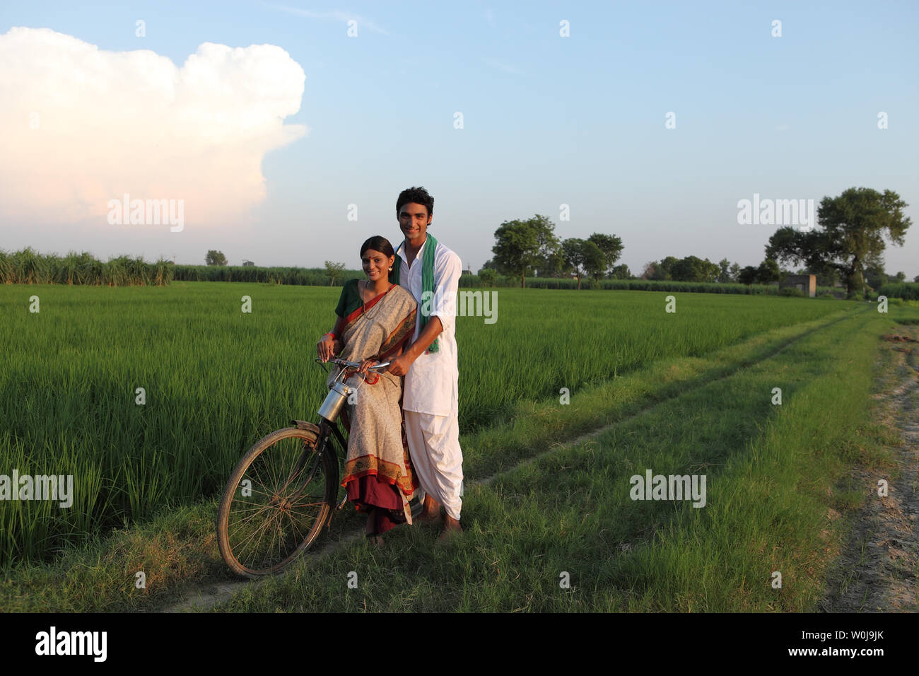 Rural couple riding on a bicycle in the field Stock Photo