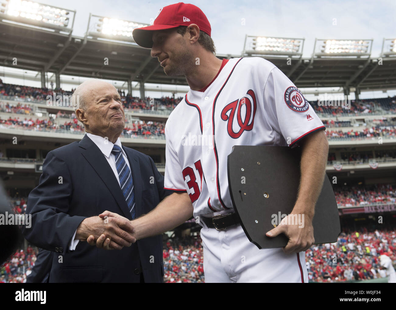 Washington Nationals starting pitcher Max Scherzer (31) shakes hands with  team owner Ted Learner after receiving the 2016 Cy Young award prior to the  Nationals season opener against the Miami Marlins at