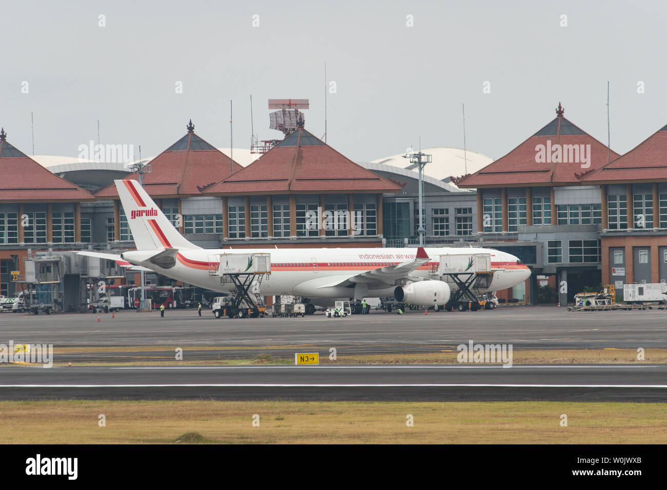 DENPASAR,BALI/INDONESIA-JUNE 08 2019: The old design of Garuda Indonesia Aeroplane prepares for passengers to board, as ground crew prepares the plane Stock Photo