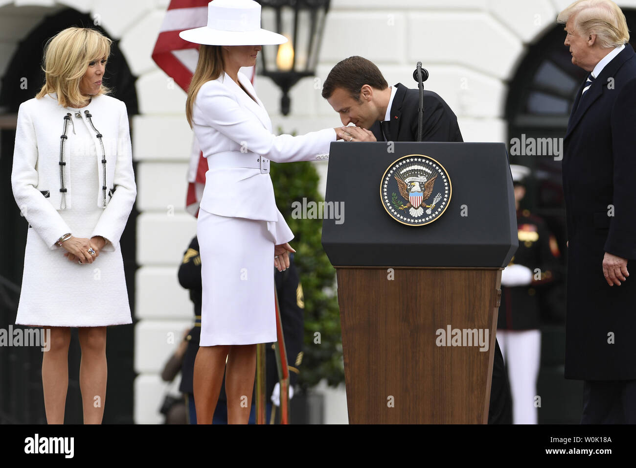 French President Emmanuel Macron kisses the hand of First Lady Melania  Trump as President Donald Trump (R) and Macron's wife Brigitte stand by at  the conclusion of State Visit welcoming remarks, at