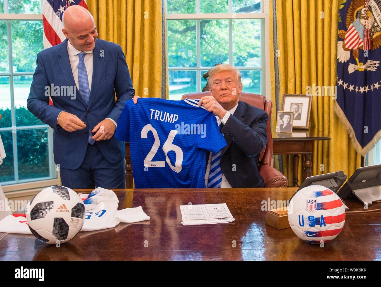 President Donald Trump holds up a World Cup jersey given to him as a gift  by President of FIFA Gianni Infantino, during a media in the Oval Office at  the White House