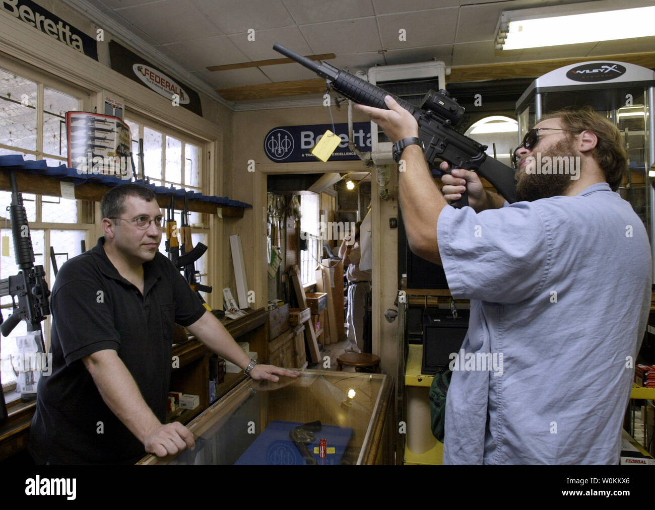 A customer (R) examines the Cold Match target gun as a salesman looks on at the Potomac Arms gun store in Alexandria, Virginia in a September 10, 2004 file photo. In the aftermath of the deadly Virginia Tech University rampage, in which 33 people were shot by student Cho Seung-Hui, many are raising questions about lax gun controls in the United States. (UPI Photo/Yuri Gripas/Files) Stock Photo