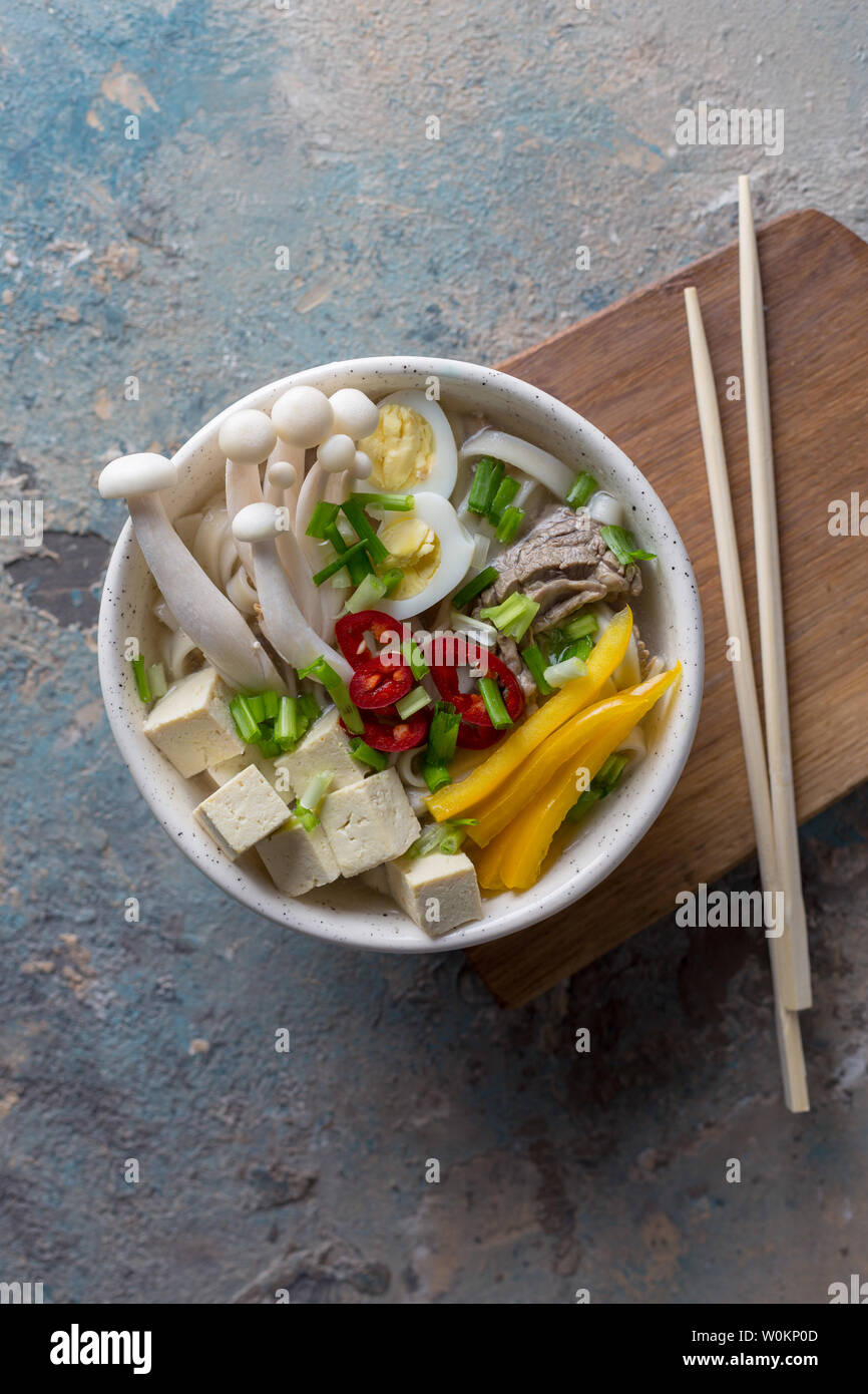 Noodle with mushrooms and vegetables in bowl. Chili, yellow paprika, tofu, onion, boiled beef and Chinese mushrooms Stock Photo