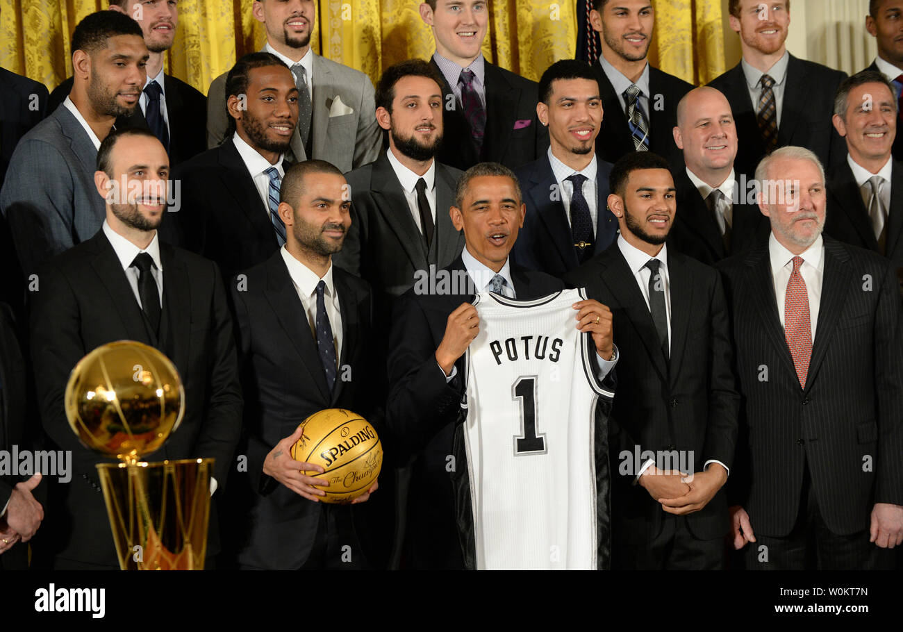 U.S. President Barack Obama receives a game jersey from San Antonio Spurs player Manu Ginobili (L) as Obama honors the 2014 NBA Champion Spurs in the East Room of the White House in Washington, DC. on January 12, 2015.  Coach Gregg Popovich is at right.  The Spurs won their fifth championship.   Photo by Pat Benic/UPI Stock Photo