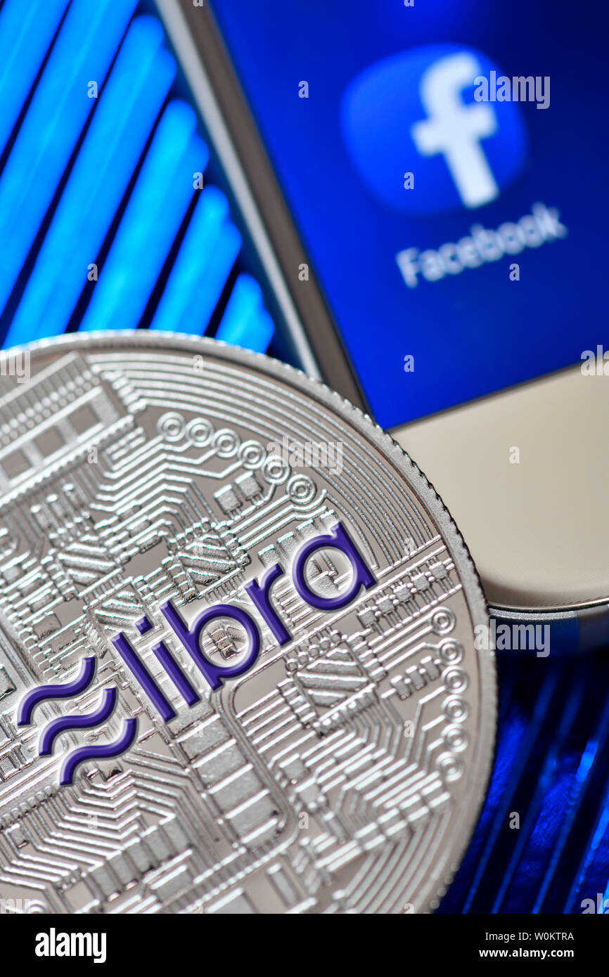 Facebook app on a smartphone screen and coin, libra cryptocurrency Stock Photo