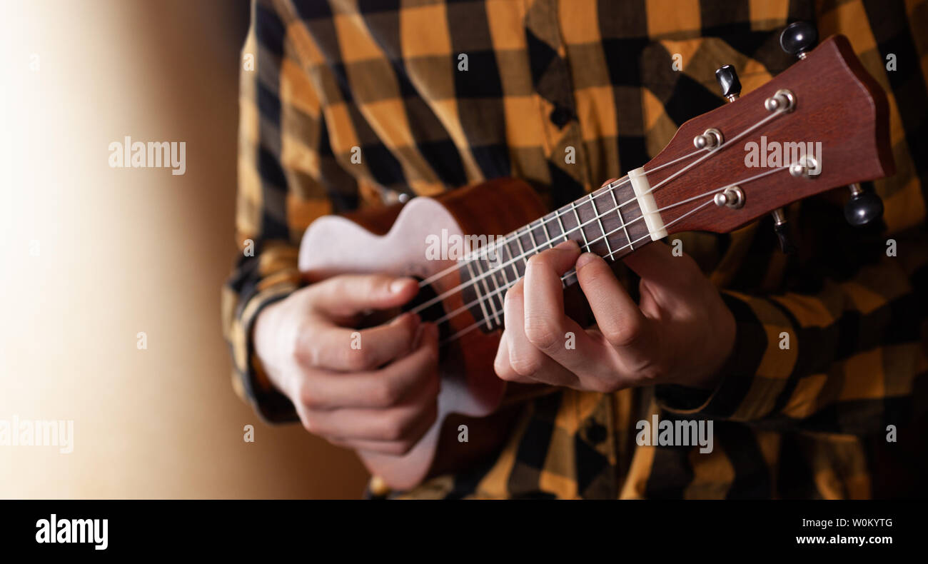 A young man playing ukulele in close up view Stock Photo