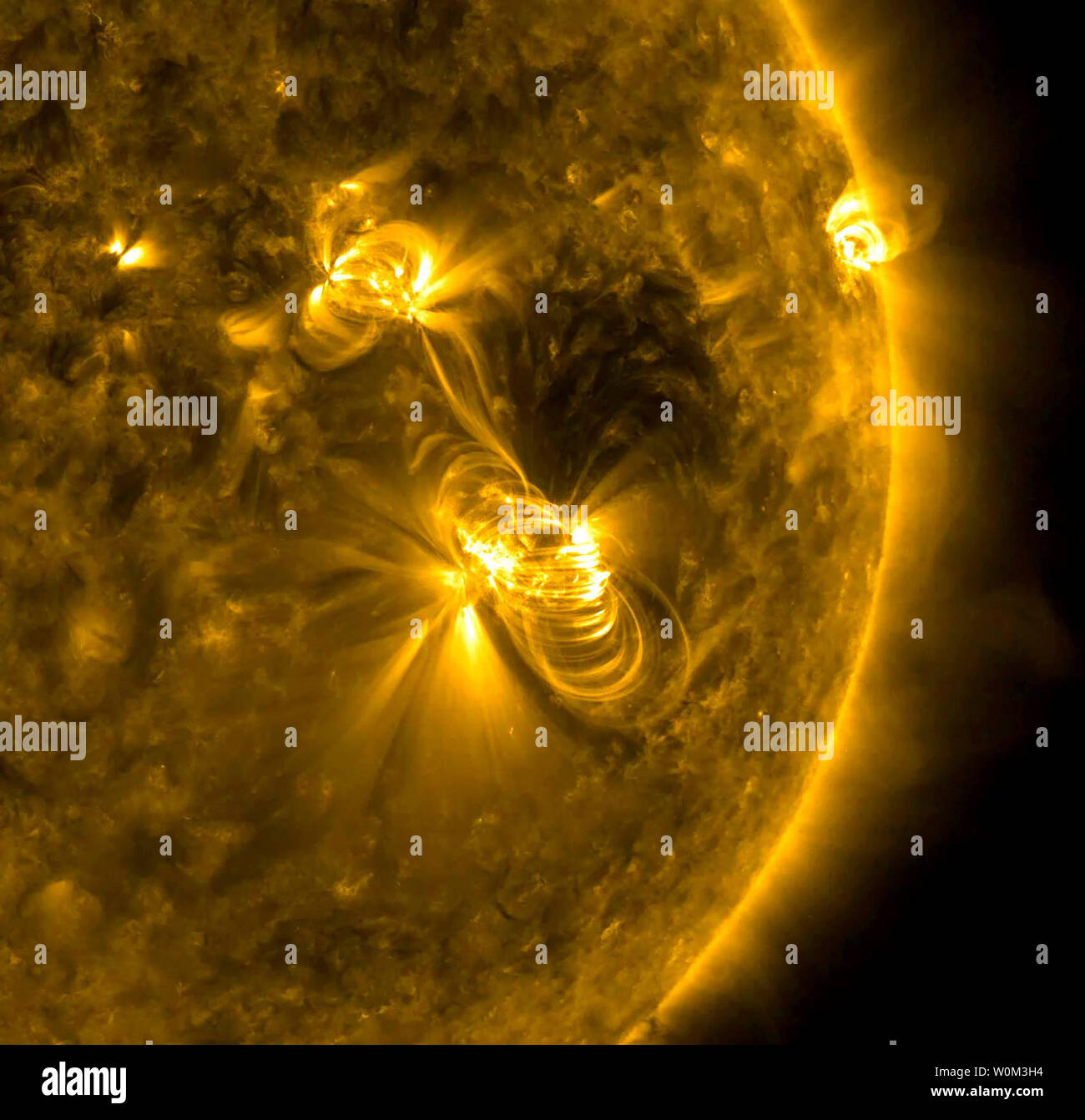 A medium-sized (M2) solar flare and a coronal mass ejection (CME) erupted from the same, large active region of the sun on July 14, 2017. The flare lasted almost two hours, quite a long duration. The coils arcing over this active region are particles spiraling along magnetic field lines, which were reorganizing themselves after the magnetic field was disrupted by the blast. Solar flares are giant explosions on the sun that send energy, light and high-speed particles into space. These flares are often associated with solar magnetic storms known as coronal mass ejections (CMEs). While these are Stock Photo