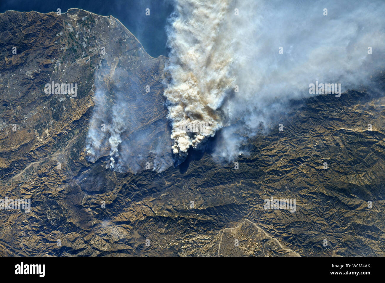 The wildfires in Southern California were photographed by NASA astronaut Randy Bresnik from the International Space Station during a flyover of the region on December 7, 2017. Watching the plumes of smoke from space, Bresnik observed, 'Today's pass over SoCal, unfortunately, doesn't look any better. The fires east of Camp Pendleton and in Baja are visible as well.' This raging inferno that has been described by firefighters as a 'war zone' started just three days ago on December 4. Burning more than 96,000 acres and 150 structures to date according to Inciweb this fire has been urged on by one Stock Photo