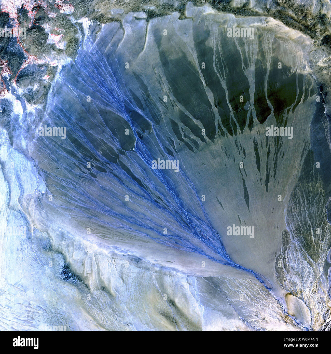 A vast alluvial fan blossoms across the desolate landscape between the Kunlun and Altun Mountains that form the southern border of the Taklimakan Desert in China’s XinJiang Province. The river appears electric blue as it runs out of the mountains at the bottom right corner of the scene and then fans out into scores of intricate, braided channels that disappear into the desert. Dry channels—the river’s former paths?—appear as silvery etchings at lower right. This scene was acquired by the ASTER instrument on NASA’s Terra satellite on May 2, 2002.   (UPI Photo/NASA) Stock Photo