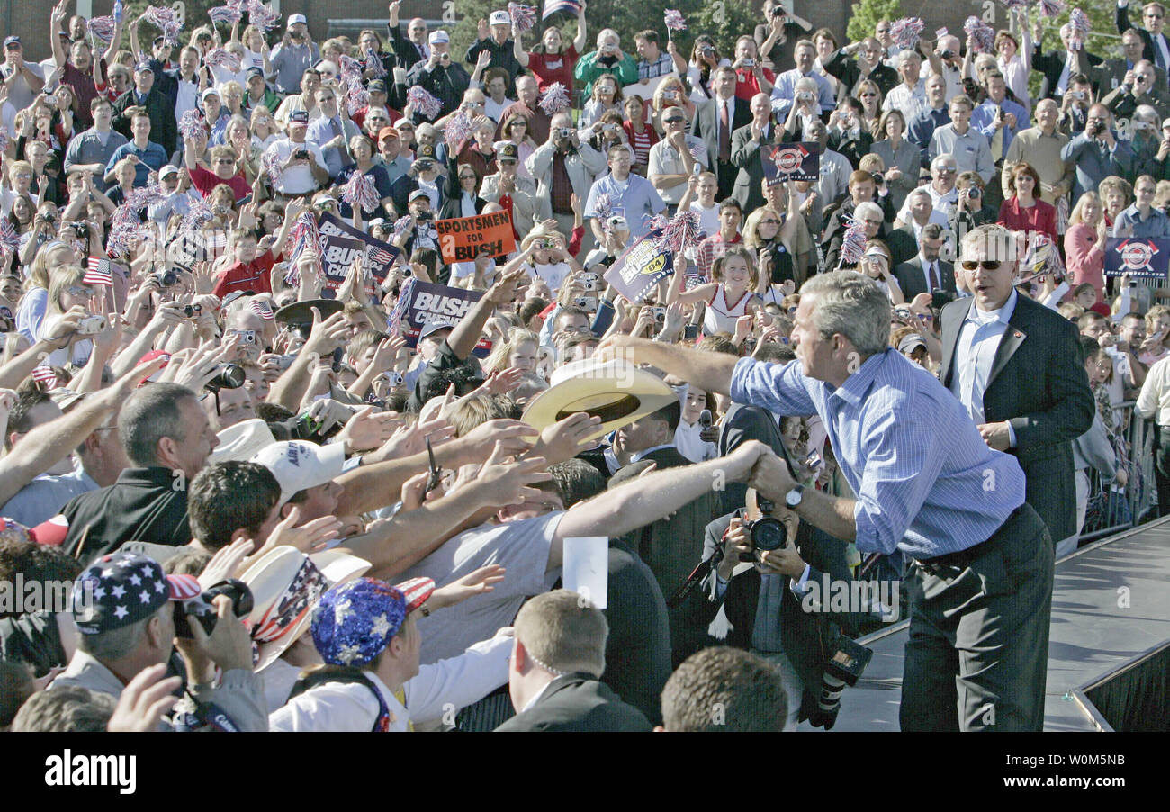 George W. Bush shakes hands and is handed a cowboy hat during a visit ...