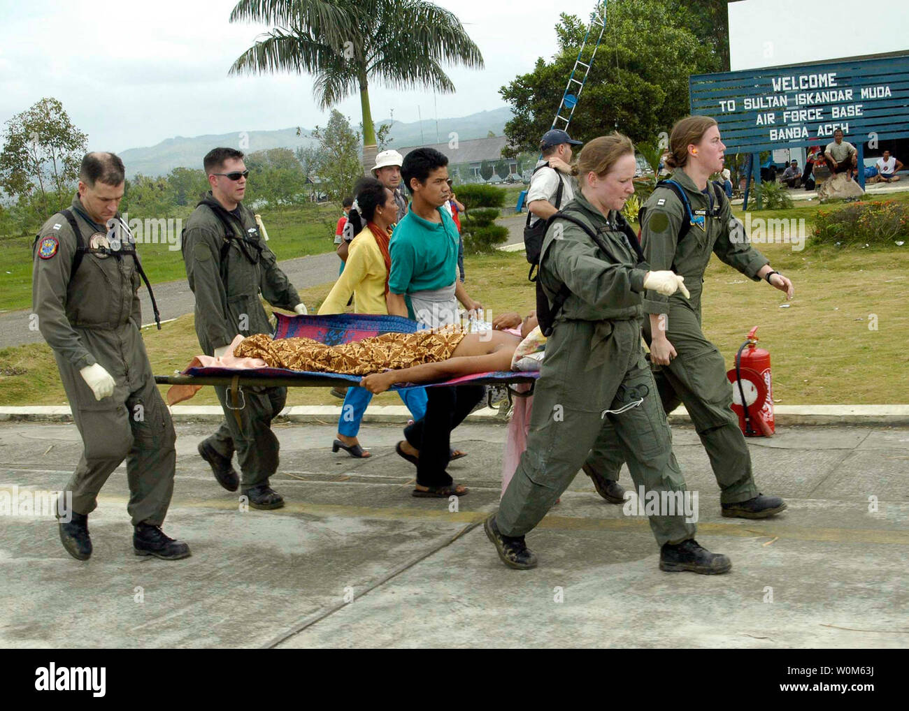 From left, Lt. Mark Banks, Chief Hospital Corpsman Jim Jones, Hospital Corpsman 1st Class Rebecca McClung, and Lt. Lisa Peterson, carry a patient on a stretcher flown-in by a U.S. Navy helicopter to a temporary triage site in Aceh, Sumatra on January 2, 2005.Medical teams from USS Abraham Lincoln (CVN 72), Carrier Air Wing Two (CVW-2) and the International Organization for Migration (IOM) set-up a triage site located on Sultan Iskandar Muda Air Force Base, in Banda Aceh, Sumatra. The two teams worked together with members of the Australian Air Force to provide initial medical care to victims o Stock Photo