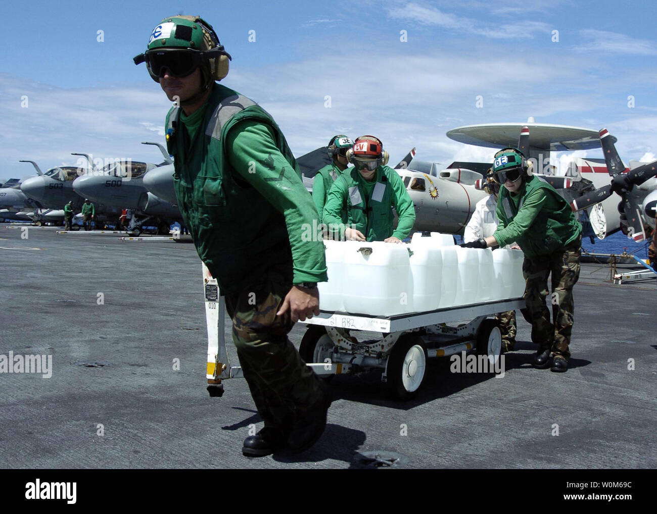 Flight deck personnel transport a weapons skid full of purified drinking water to an awaiting SH-60B Seahawk helicopter, assigned to the 'Saberhawks' of Helicopter Anti-Submarine Squadron Light Four Seven (HSL-47), aboard USS Abraham Lincoln (CVN 72) on Jan. 10, 2005, in the Indian Ocean. Helicopters assigned to Carrier Air Wing Two (CVW-2) and Sailors from Abraham Lincoln are supporting Operation Unified Assistance, the humanitarian operation effort in the wake of the Tsunami that struck South East Asia.    (UPI Photo/Tyler J. Clements/US NAVY) Stock Photo