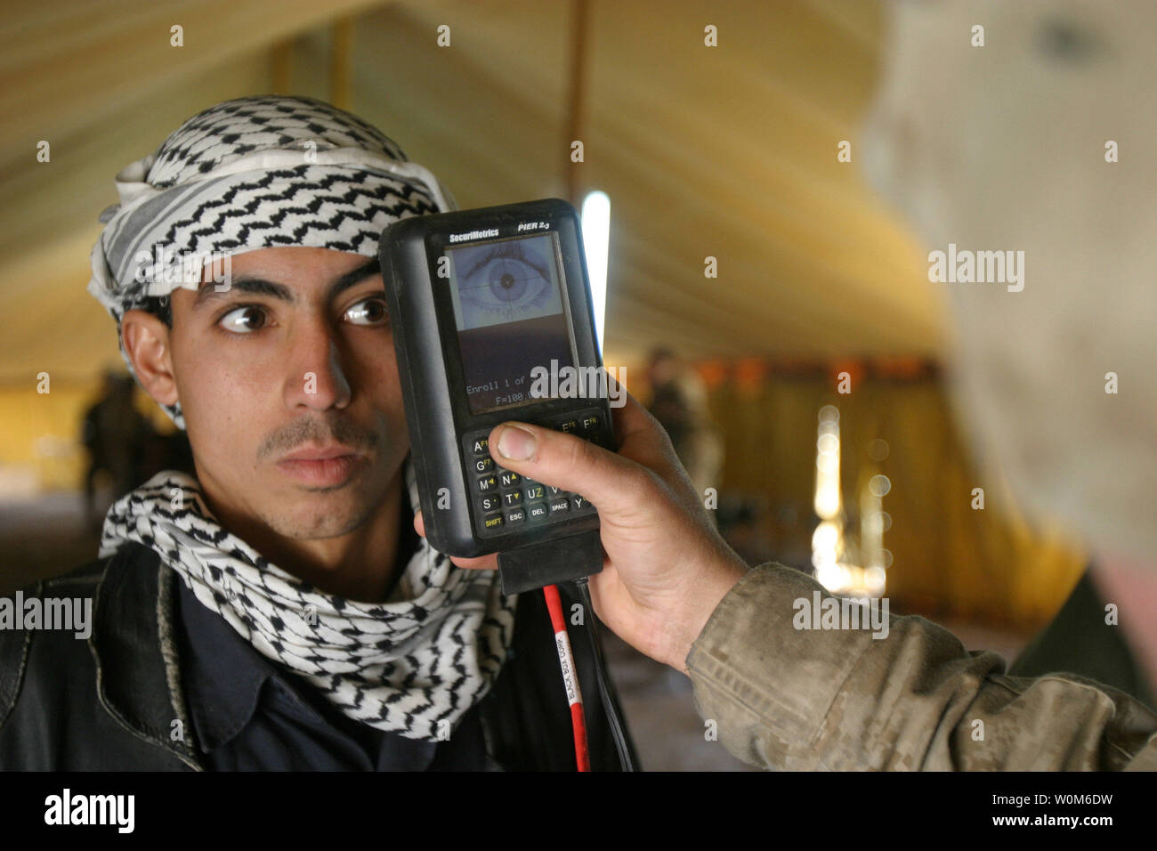 Marine Lance Cpl. Luis Molina scans an Iraqi citizen's retina at Brahma Park in Fallujah, Iraq, on Jan 25, 2005.  U.S. Marines are utilizing a Biometric Analysis Tracking System to record and identify Iraqi civilians entering the battle torn city of Fallujah in an attempt to find and identify insurgent forces.  The tracking system uses thumbprints, a photograph of the face, and a retinal scan to establish positive identity.  (UPI Photo/Jonathan C. Knauth/Marines) Stock Photo