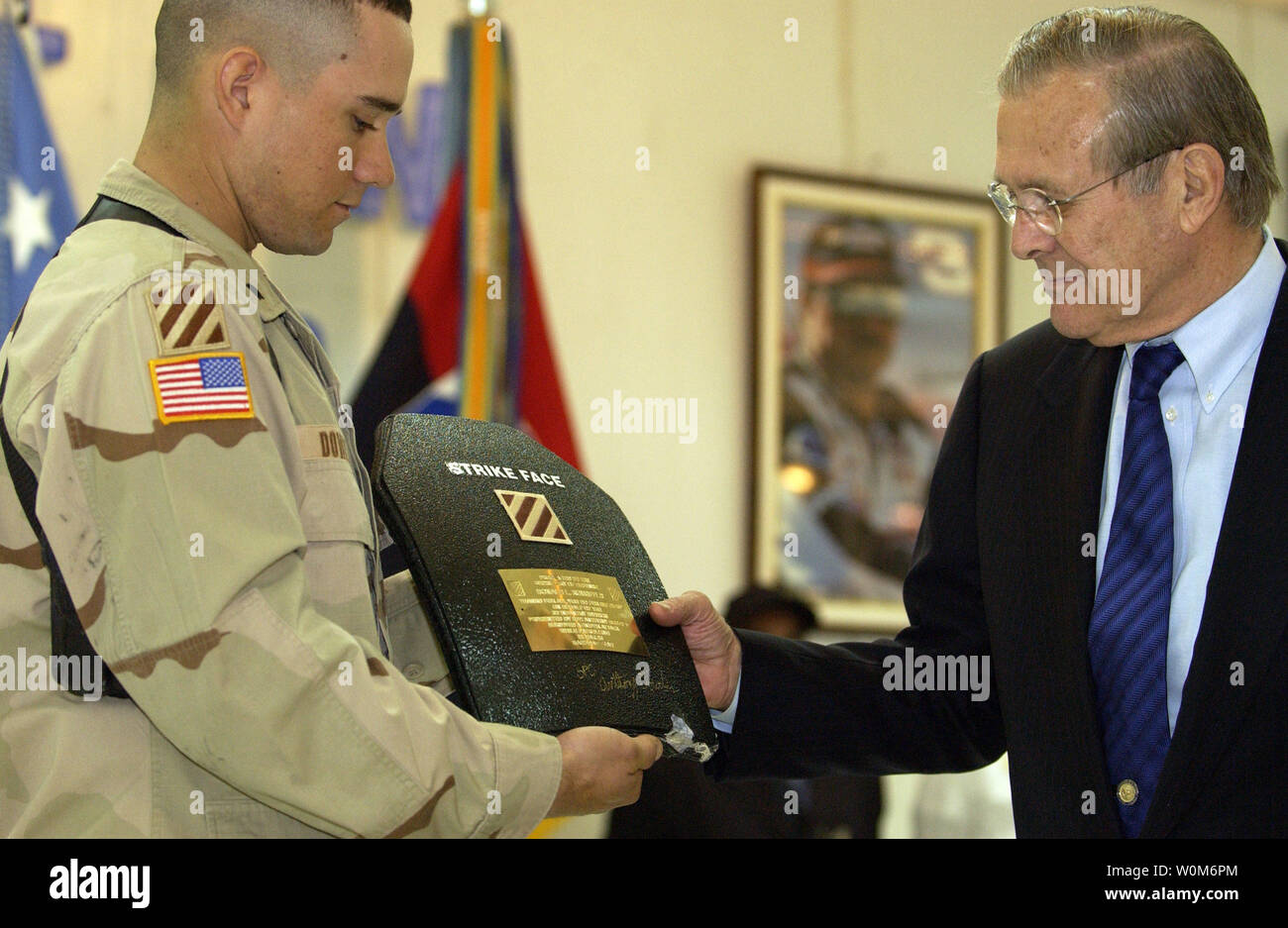 Army Spc. Anthony Dowden of the 3rd Infantry Division presents a plaque made from a piece of armor that saved him from a sniper's bullet to Secretary of Defense Donald H. Rumsfeld in Baghdad, Iraq, on April 12, 2005.   Rumsfeld is in Iraq to visit with U.S. and coalition forces and to meet with the newly elected members of the Iraqi government.  (UPI Photo/ Cherie A. Thurlby/Air Force) Stock Photo