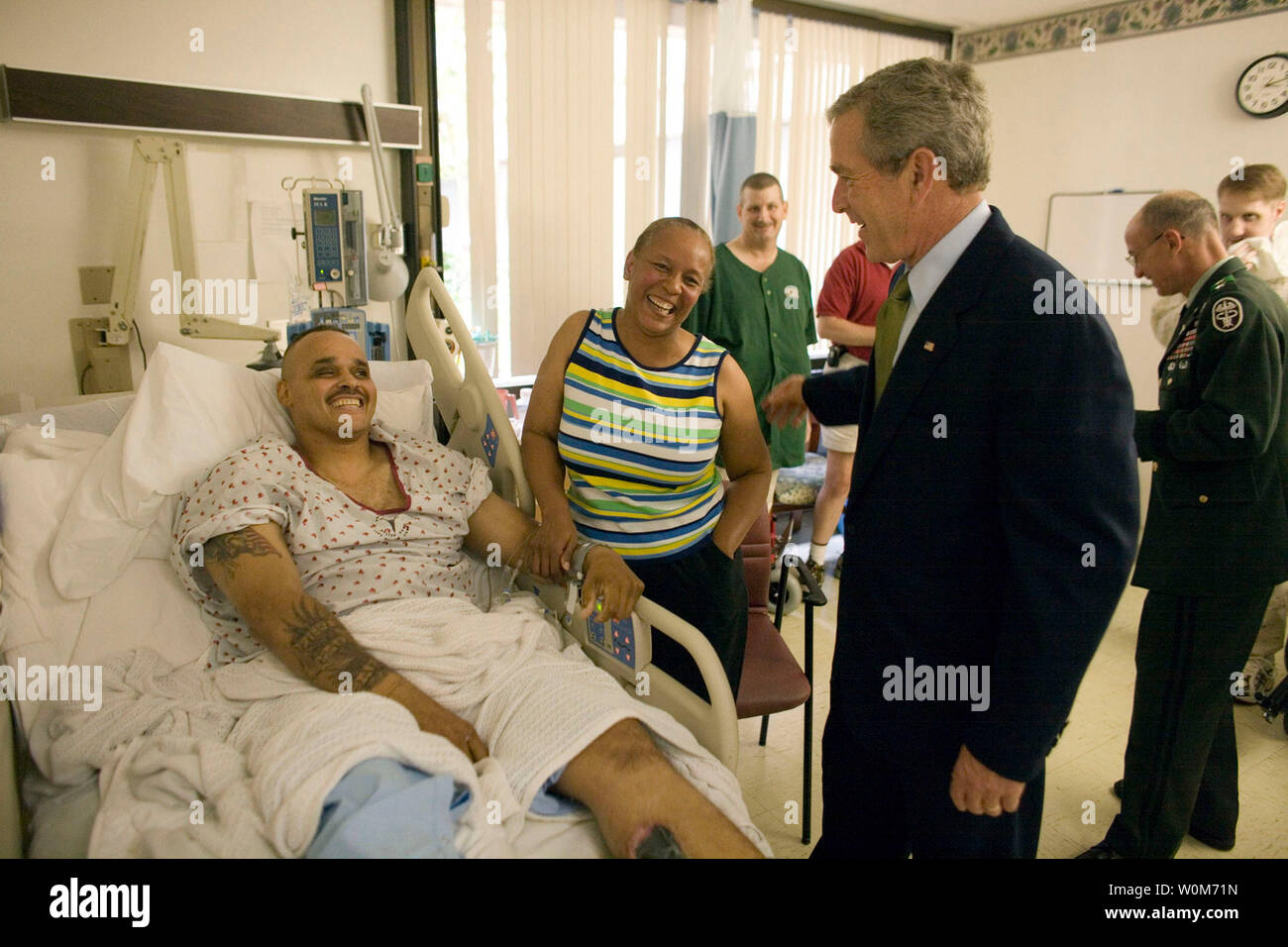 President George W. Bush shares a light moment with Sgt. John Iverson and his wife, Pamela, during the President's visit Friday, July 1, 2005, to Walter Reed Army Medical Center.  The Long Beach, California soldier is recovering from injuries sustained while serving in Iraq.  (UPI Photo/Eric Draper/White House) Stock Photo