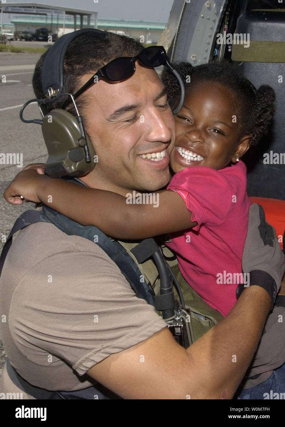 A young Hurricane Katrina survivor hugs her rescuer Staff Sgt. Mike Maroney after she was relocated to the New Orleans International Airport on Sept. 7, 2005. Maroney is a pararescue from the 58th Rescue Squadron, Nellis Air Force Base, Nev. (UPI Photo/Veronica Pierce/USAF) Stock Photo
