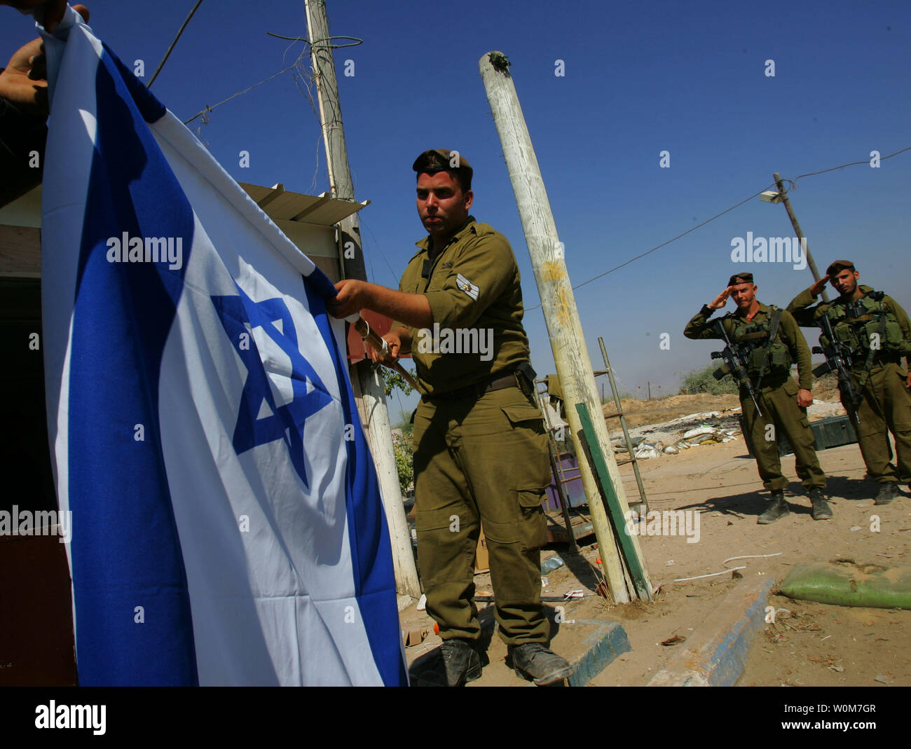 Army officers salute as Israeli soldiers from the Golani brigade lower the flag as they prepare to withdraw September 11, 2005 from the Yareach outpost in the southern Gaza Strip. Israel is expected to withdraw the last of their troops from the Gaza Strip within hours bringing an historical end to 38 years of occupation of the Palestinian territory. (UPI Photo/David Silverman/Pool) Stock Photo