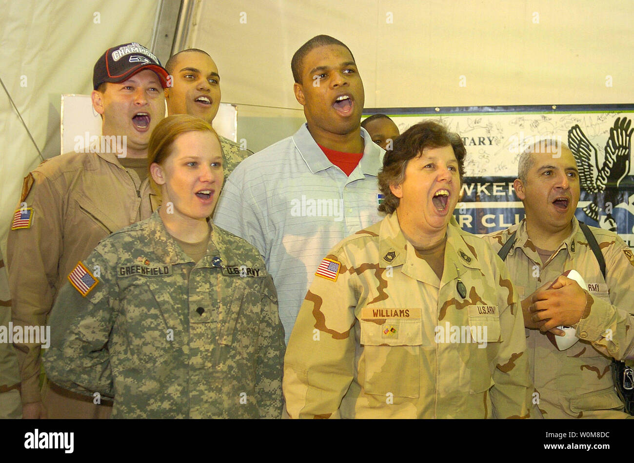 Seattle Seahawk's Bryce Fisher (civilian clothes) and Seahawks fans record a cheer to be used on the Seahawk's Jumbotron next season during a USO visit to Camp Eggers in Kabul, Afghanistan, April 4, 2006.  Fisher was joined by MSgt. Traci Williams (C), who is the Seahawks' Military Liason and is now deployed in Afghanistan. US troops (L-R) Spc. Jessica Greenfield, Evansville, IN, and MSgt. Jesus Ruiz, San Antonio, TX  joined in. The USO and NFL are marking a 40-year relationship of supporting US military with morale-boosting visits around the world.   (UPI Photo/Mike Theiler/USO) Stock Photo