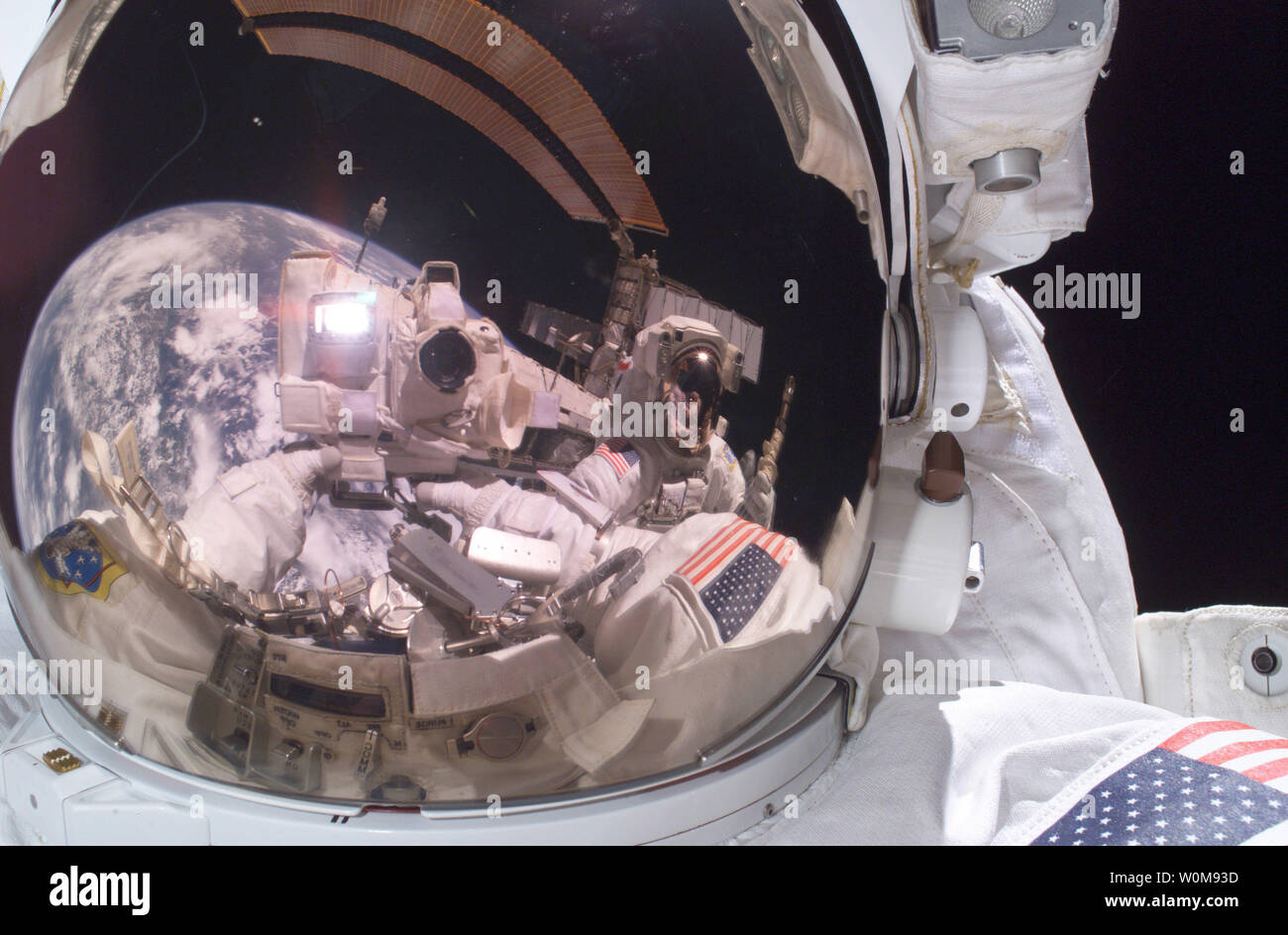 Astronaut Michael Fossum takes a self-portrait on July 8, 2006 during a space walk or extravehicular activity while the Discovery orbiter is docked with the International Space Station. Turning his camera to snap a picture of his own helmet visor, he also recorded the reflection of his fellow mission specialist, Piers Sellers, near picture center and one of the space station's gold-tinted solar power arrays arcing across the top.  (UPI Photo/Michael Fossum/NASA) Stock Photo
