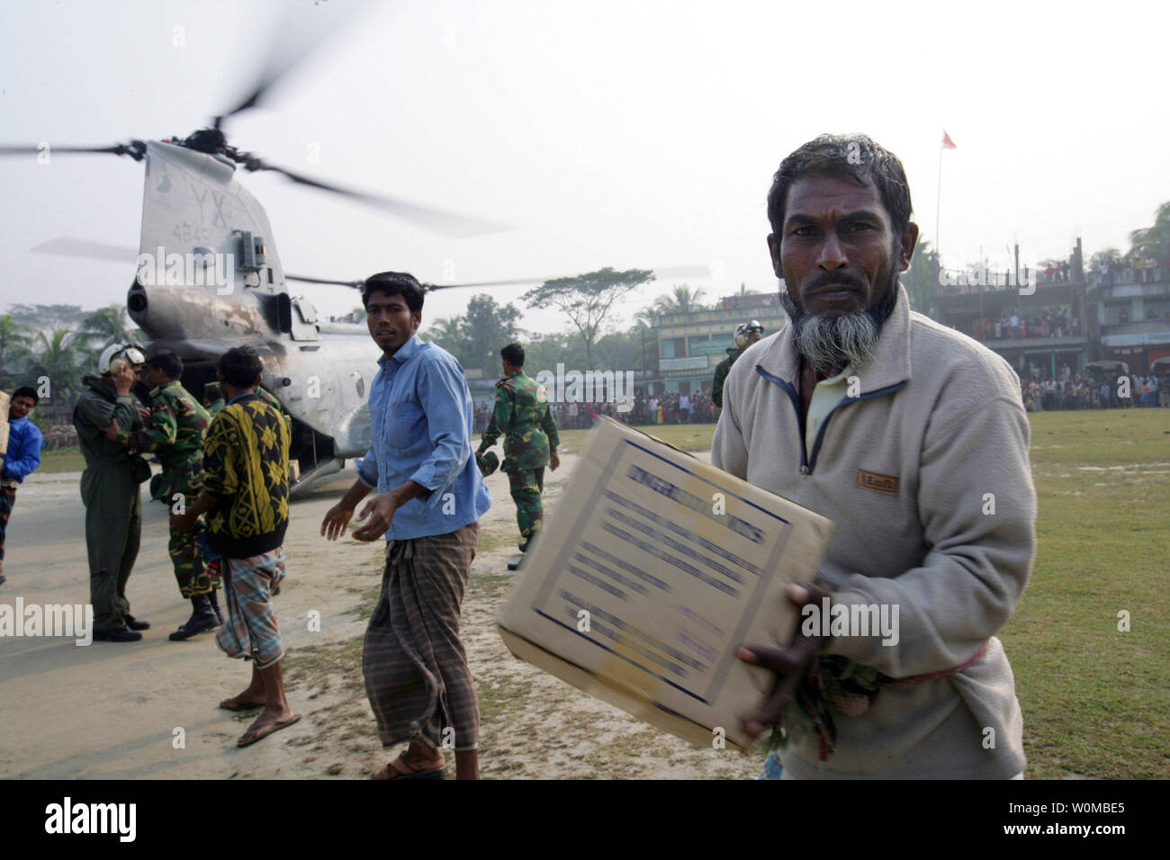 Bangladeshi men help to unload food rations from a Marine CH-46E  Helicopter in Bawfal, Bangladesh on December 4, 2007. The amphibious assault ship USS Tarawa and the embarked 11th MEU are conducting Humanitarian Assistance/Disaster Relief efforts in response to the government of Bangladesh's request after Tropical Cyclone Sidr struck their southern coast Nov. 15. (UPI Photo/Bryson K. Jones/USN) Stock Photo