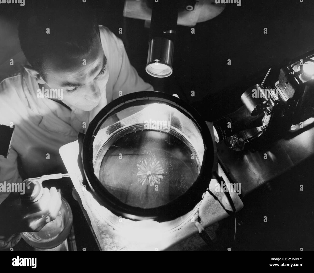 In this 1957 photograph, an unnamed NACA physicist studies alpha rays in a continuous cloud chamber. NACA, the National Advisory Council on Aeronautics, was NASA's predecessor. (UPI Photo/NASA) Stock Photo