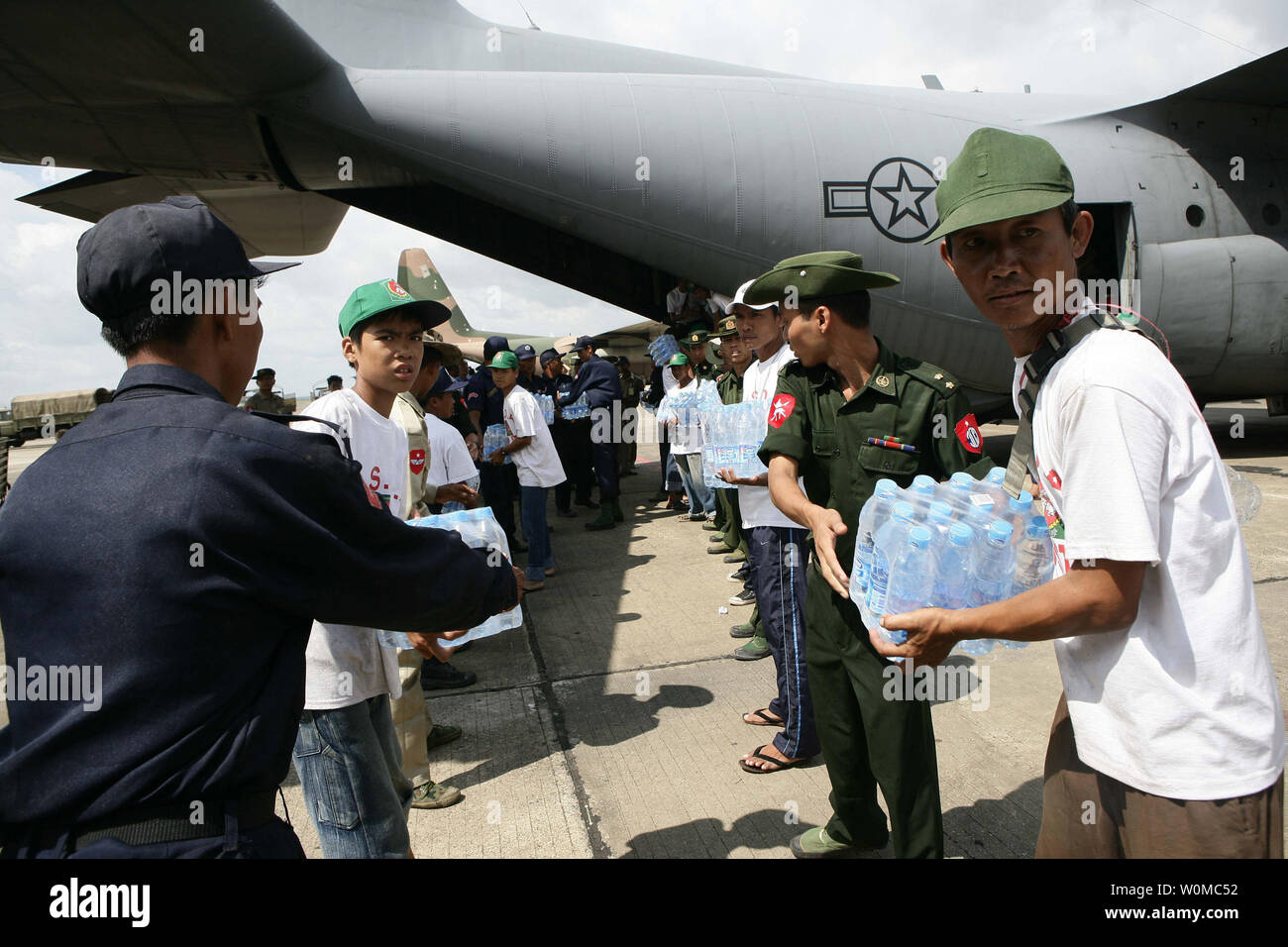 Burmese service members form a line to unload water supplies from a U.S. Air Force C-130 Hercules aircraft at Rangoon International Airport in Myanmar on May 12, 2008. The shipment of water, mosquito nets and blankets arrived on the first of three planned relief flights to provide aid to citizens devastated by Tropical Cyclone Nargis. (UPI Photo/Andres Alcaraz/U.S. Marine Corps) Stock Photo